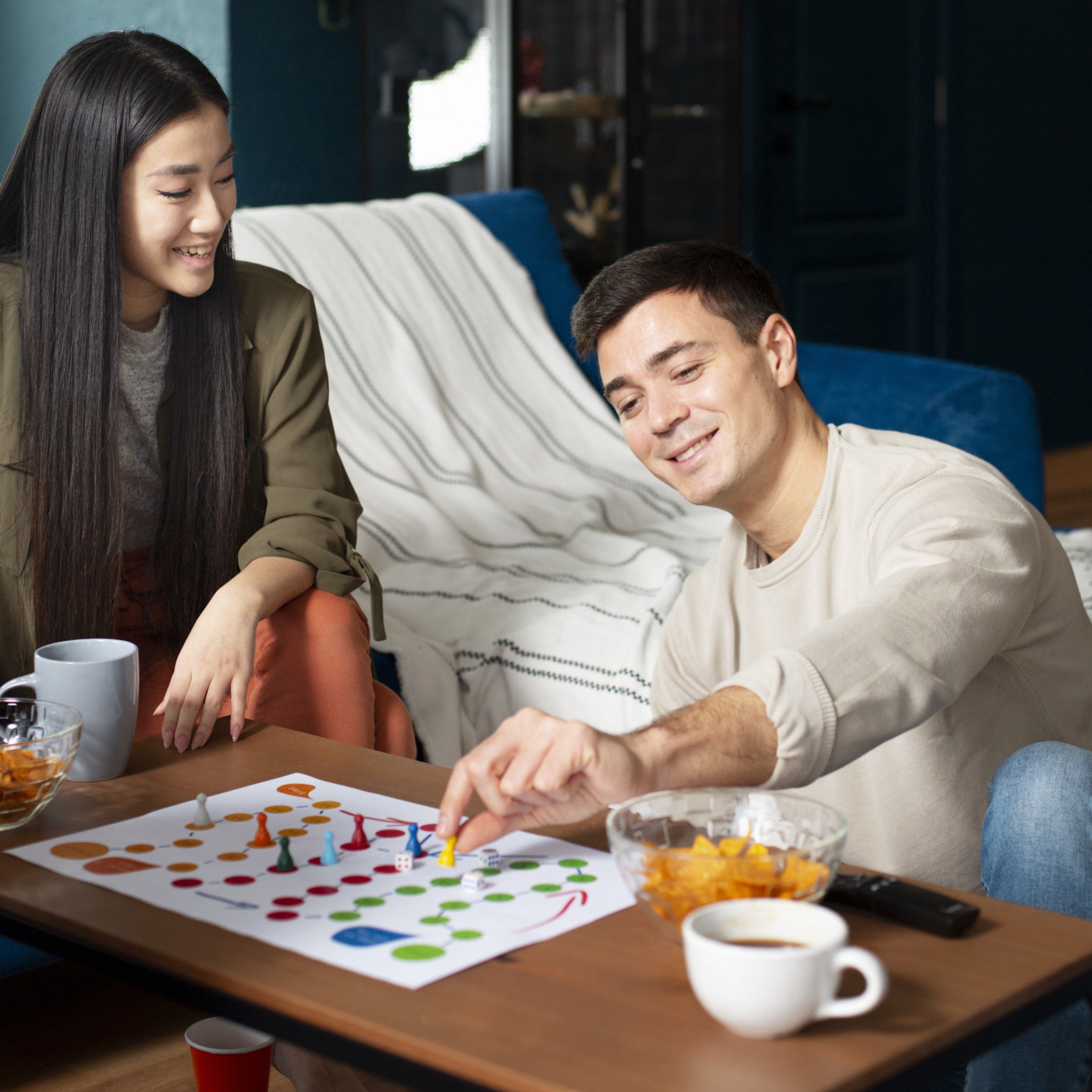 Couple jouant ensemble &agrave; un jeu de soci&eacute;t&eacute; en souriant